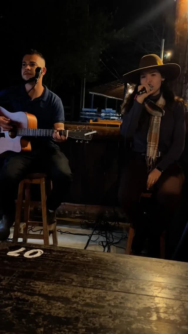 Layra Mota cantando ao lado do músico no violão, em show noturno